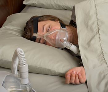 Senior woman using cpap machine to stop choking and snoring from obstructive sleep apnea